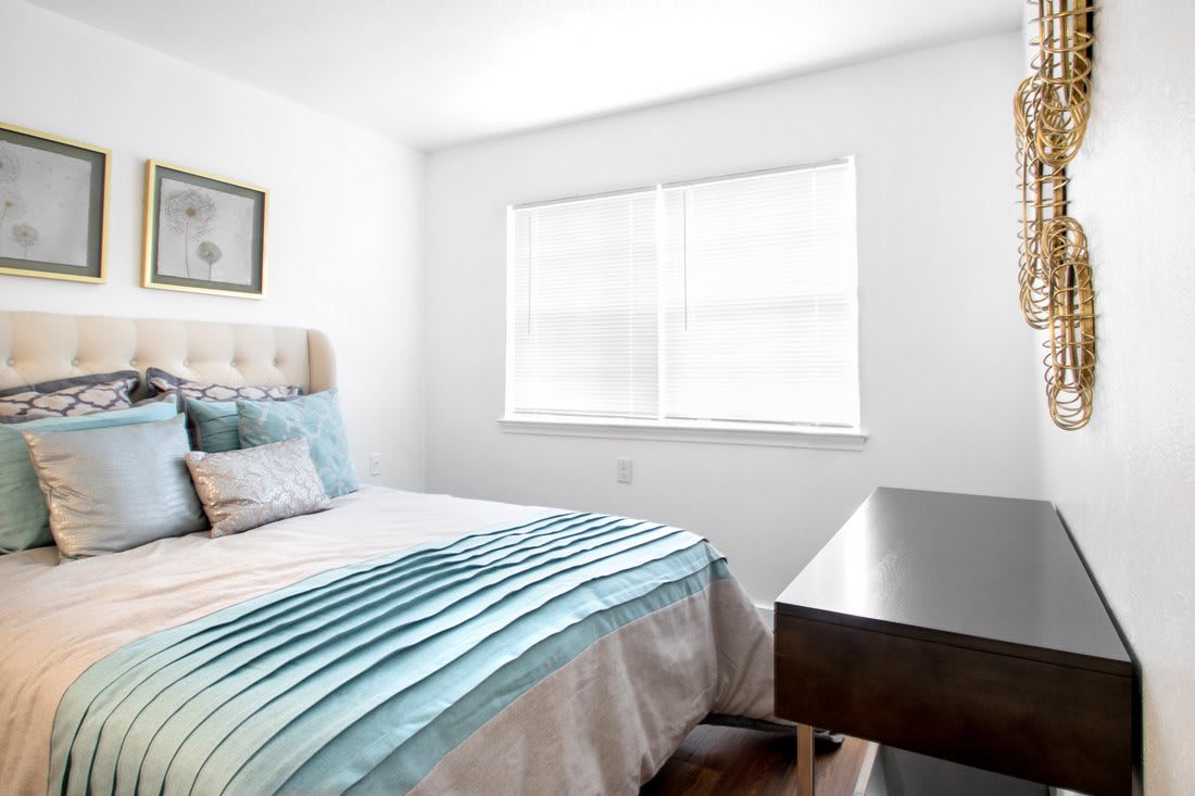 A bright bedroom featuring a neatly made bed and a large window allowing natural light to fill the room.