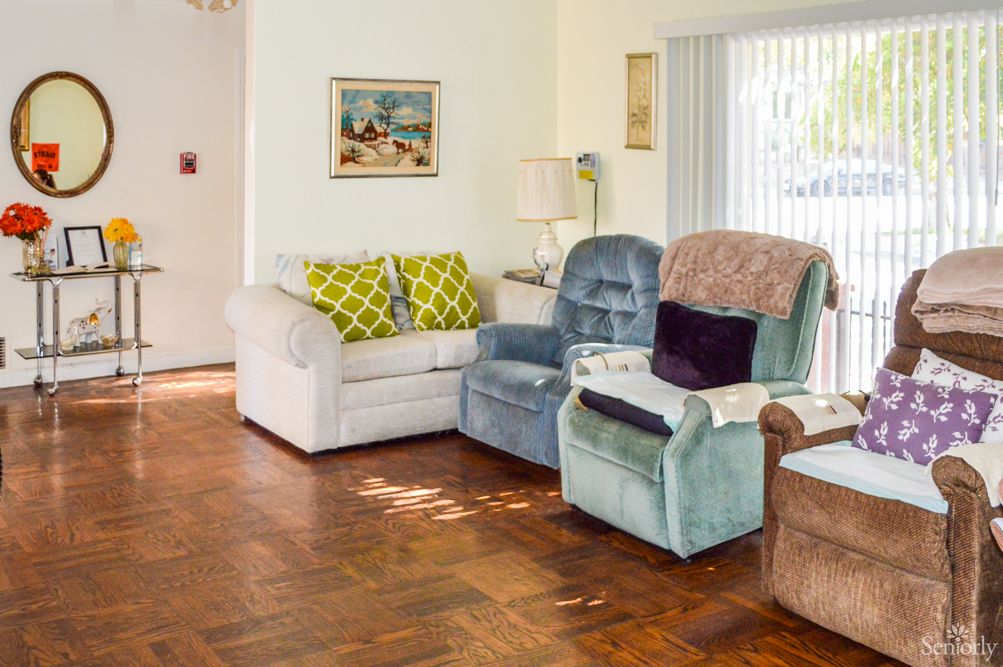 A cozy living room with a sofa, two armchairs, and decorative cushions on a wooden floor.