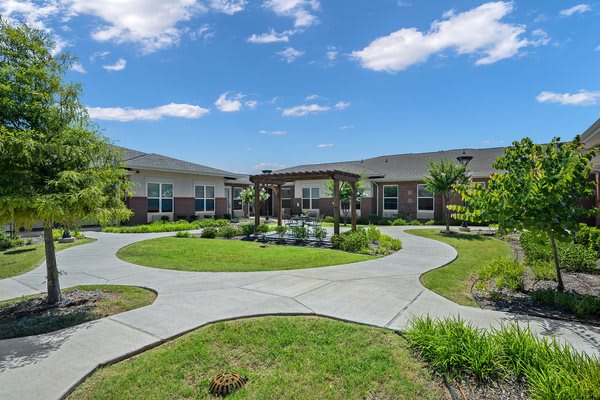 A well-maintained courtyard with a circular pathway surrounded by green landscaping under a blue sky.