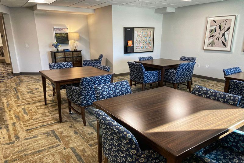 A neatly arranged dining room with wooden tables and patterned chairs.