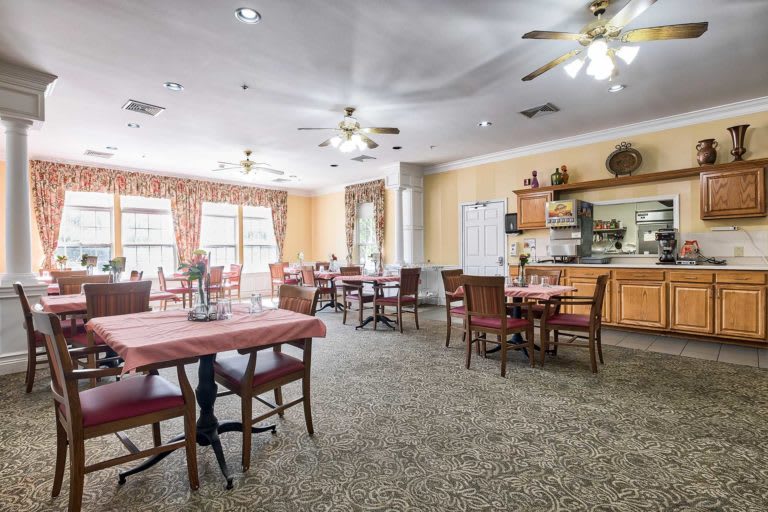A cozy dining area with several tables and chairs, adorned with soft lighting and ceiling fans.