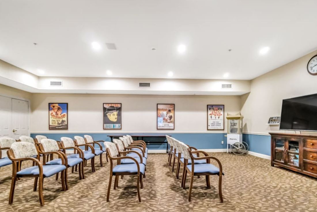 An empty conference room setup with rows of chairs and movie posters on the wall.
