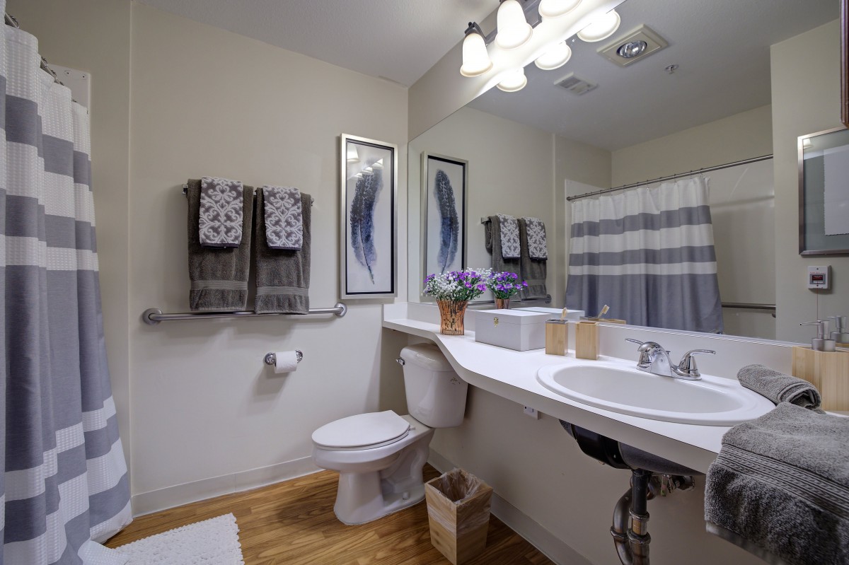 A modern bathroom with coordinated decor, featuring a large mirror, sink, toilet, and a striped shower curtain.