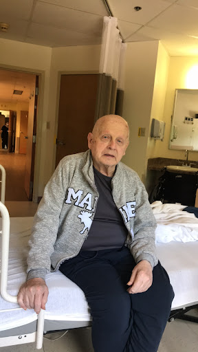An elderly man sitting in a hospital room.