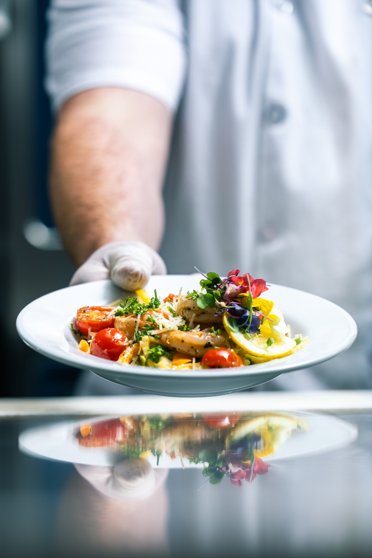 A chef presents a beautifully plated gourmet dish with vibrant colors and fresh ingredients.