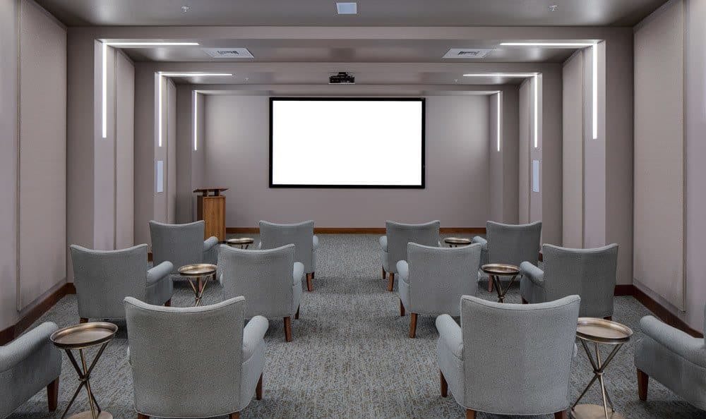 A modern conference room with a projector screen and comfortable seating.