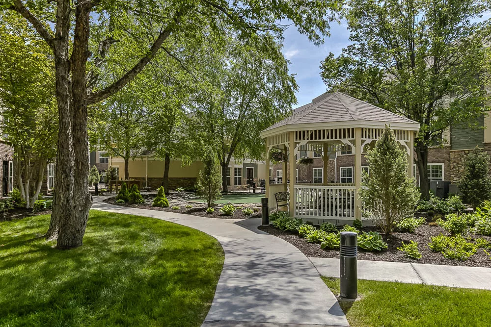 A serene park setting featuring a gazebo surrounded by lush greenery and a winding pathway.