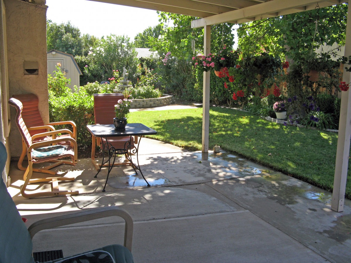 A cozy patio overlooking a lush garden with outdoor furniture and vibrant greenery.