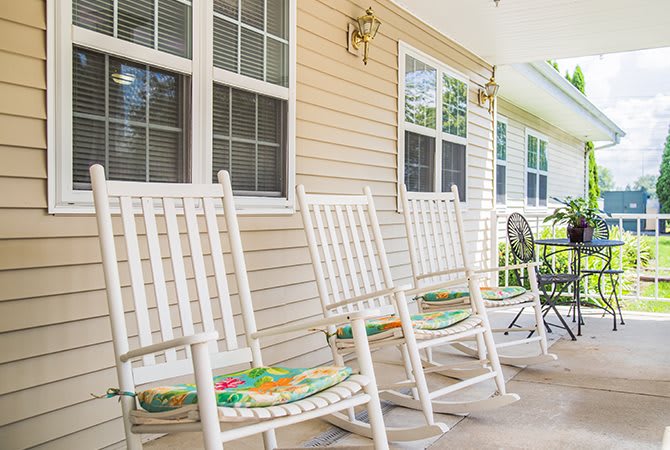 A cozy porch featuring white rocking chairs with colorful cushions.