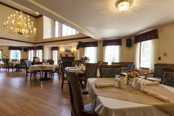 An elegant dining room with neatly arranged tables and chandeliers.