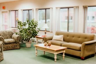A cozy living room with a sofa, coffee table, and large windows letting in natural light.