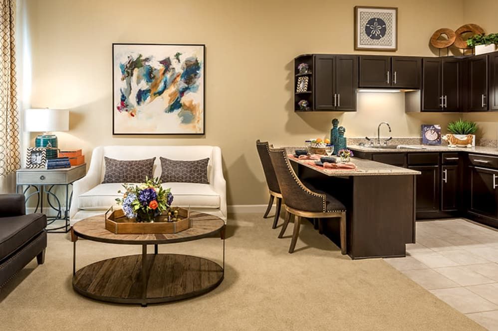 A modern living room with a cozy seating area, abstract artwork, and an adjoining kitchen space.