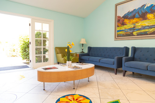 A bright and inviting living room featuring blue sofas, a stylish coffee table, and vibrant artwork.
