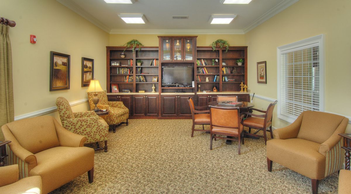 A cozy library room with bookshelves, a TV, seating area, and a table.