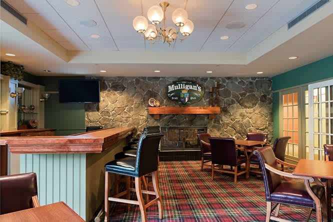 Cozy pub interior with rustic stone wall and comfortable seating.