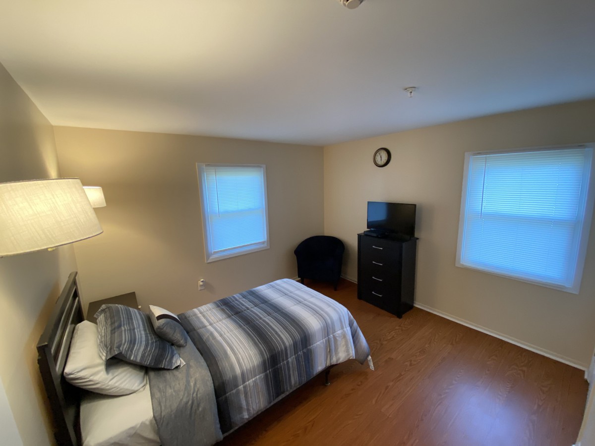 A cozy bedroom with a bed, television, and wooden flooring.