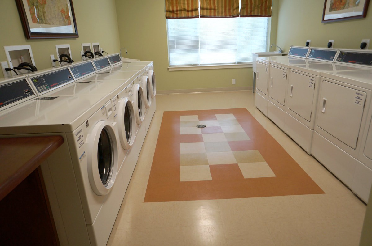 A clean laundry room with multiple washing machines and tiled flooring.