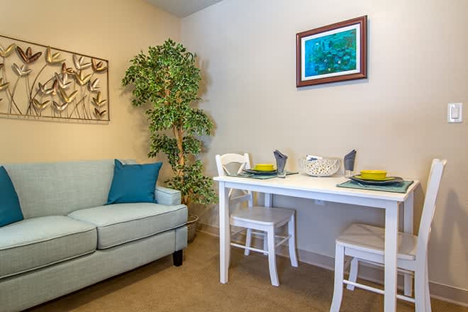 A cozy living room with a sofa and a small dining table set for two.