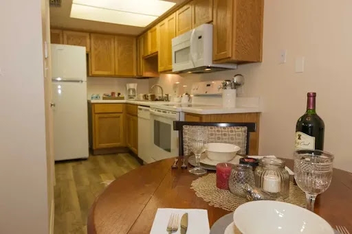 A cozy modern kitchen featuring wood cabinetry, essential appliances, and a welcoming dining area.