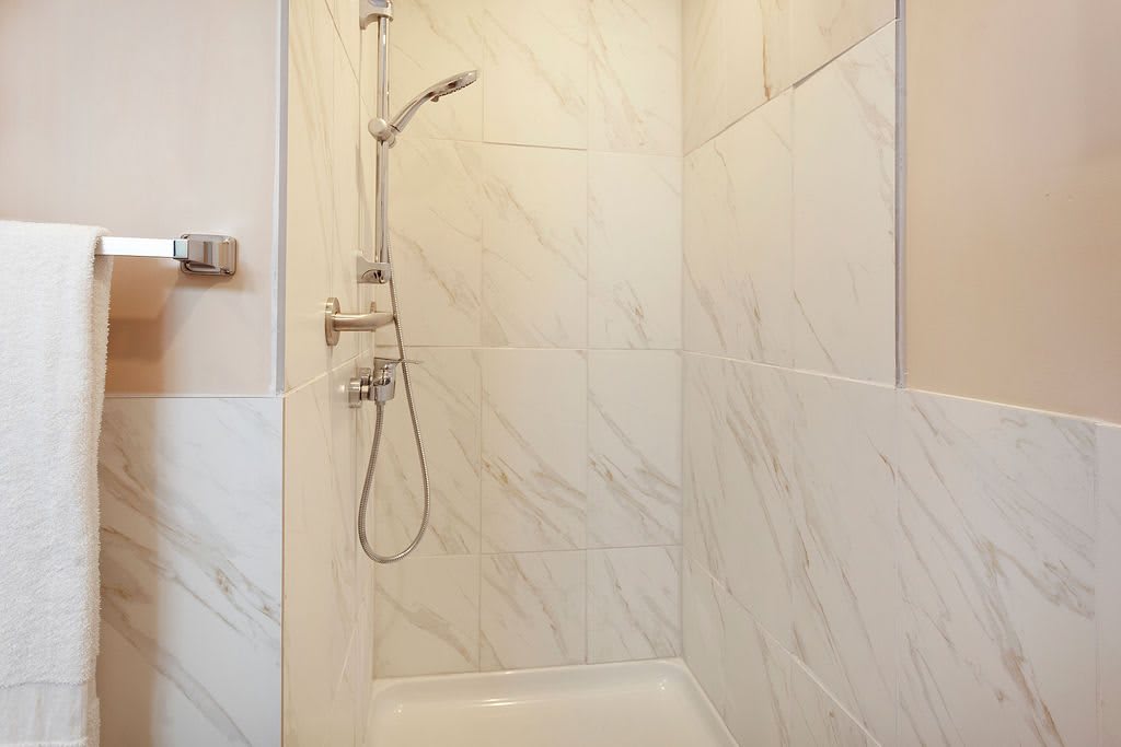 A modern shower area with marble-patterned tiles.