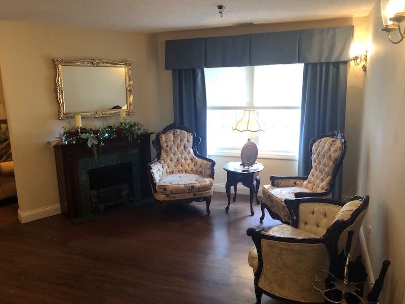 A cozy living room with classic decor, featuring a pair of patterned armchairs and a small table by the window.