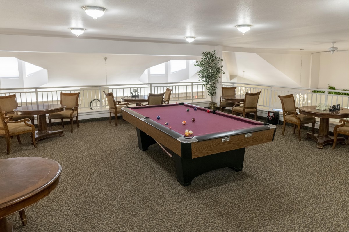 A cozy game room featuring a billiards table and seating area.