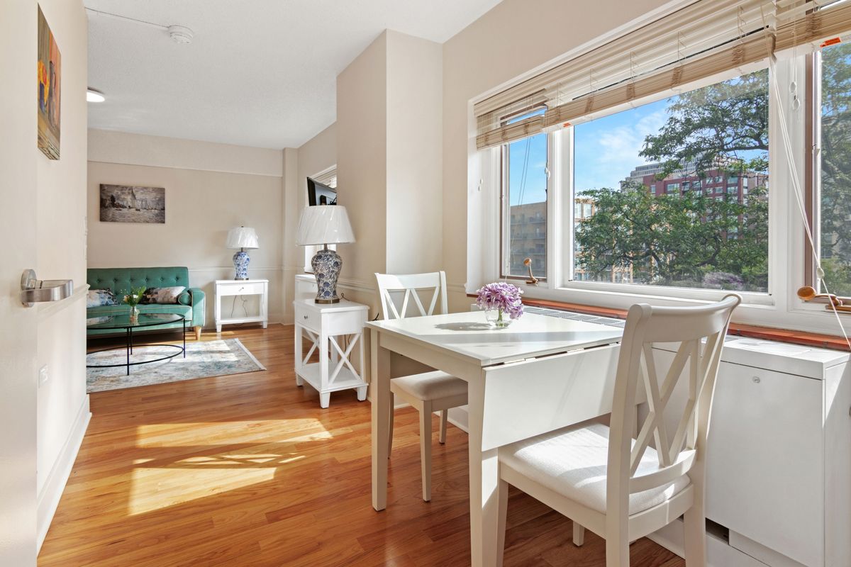 A bright and cozy living area with a dining table near a sunlit window.