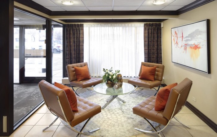 A modern lounge area with stylish chairs and a glass center table, illuminated by natural light.