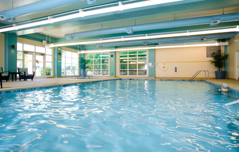 An indoor swimming pool with large windows and clean, clear water.