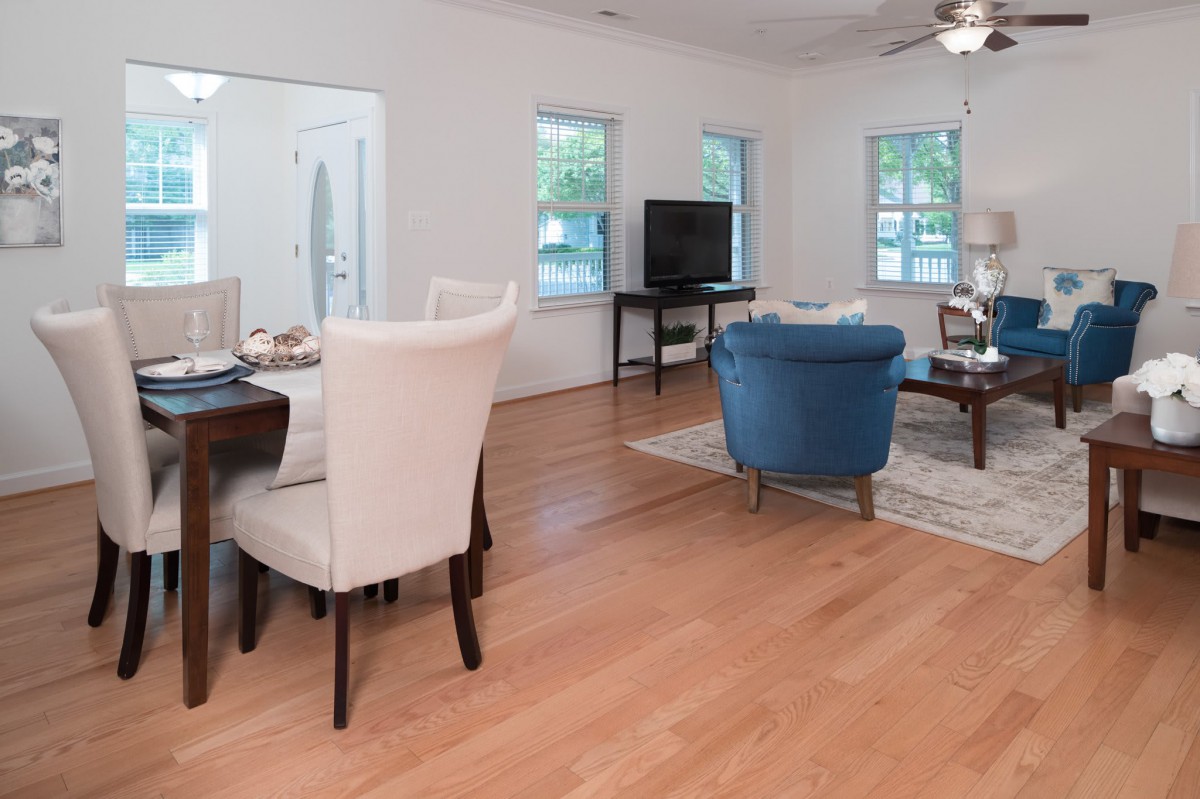 A modern open-plan living and dining area with hardwood flooring, featuring comfortable seating and a television.