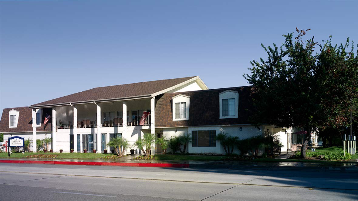 A two-story motel with balconies and a small garden area alongside the street.