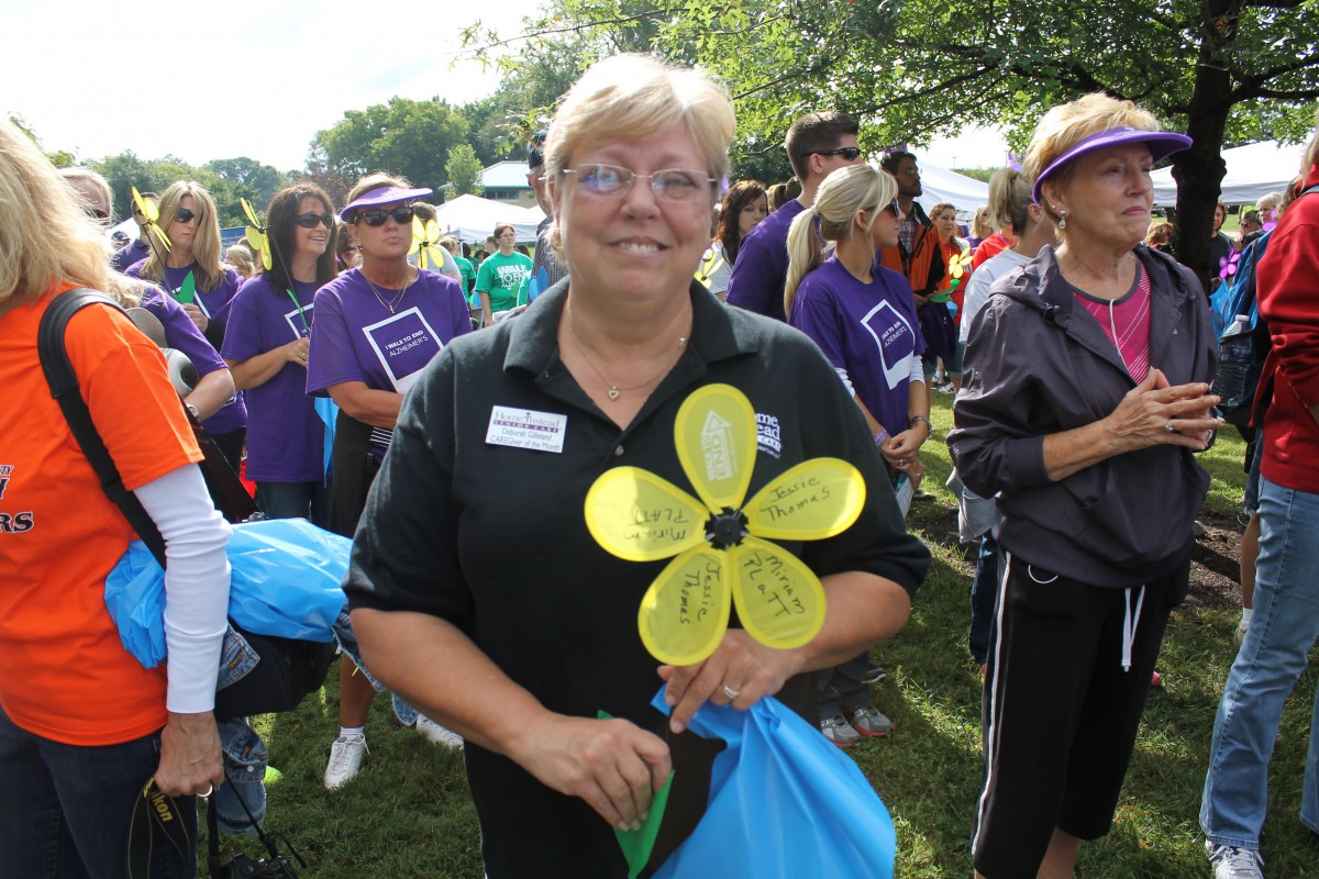 A group of people gather outdoors, with one person holding a yellow flower prop.
