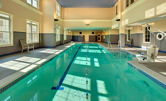 An inviting indoor swimming pool with natural light streaming in.