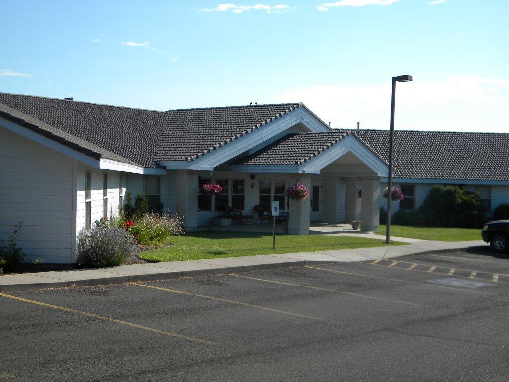 A view of a residential-style building with a parking lot in front.