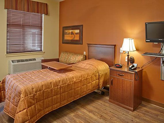 A cozy bedroom with a single bed, nightstand, and warm brown decor.