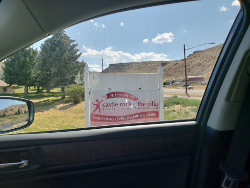 A business sign viewed from inside a car, set against a clear sky and grassy area.
