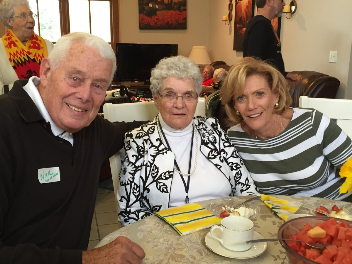 Three people sitting together at a table, smiling in a cozy indoor setting.