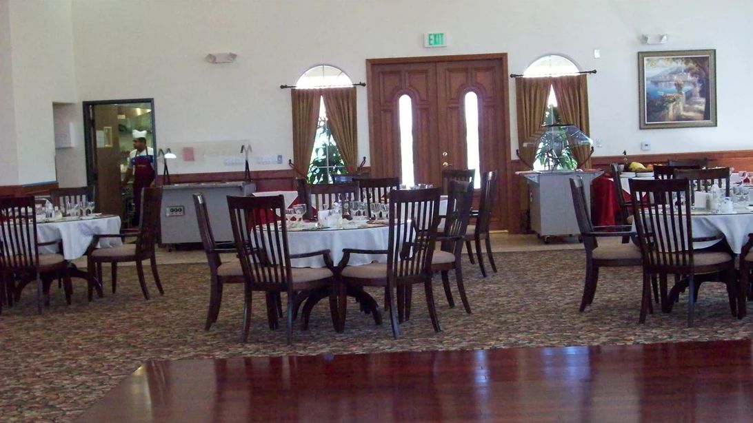 An elegantly set dining area with round tables and wooden chairs inside a restaurant.