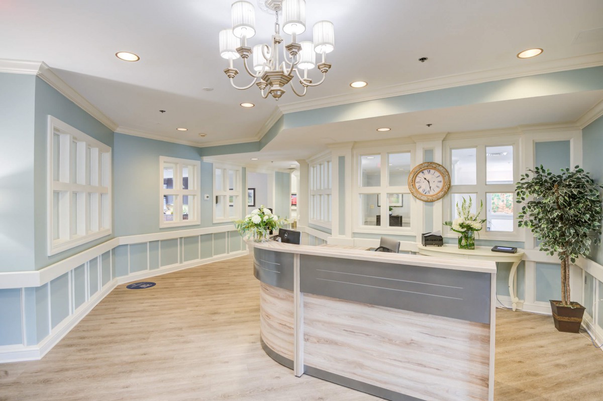 A beautifully designed reception area with a modern desk, elegant chandelier, and welcoming decor.