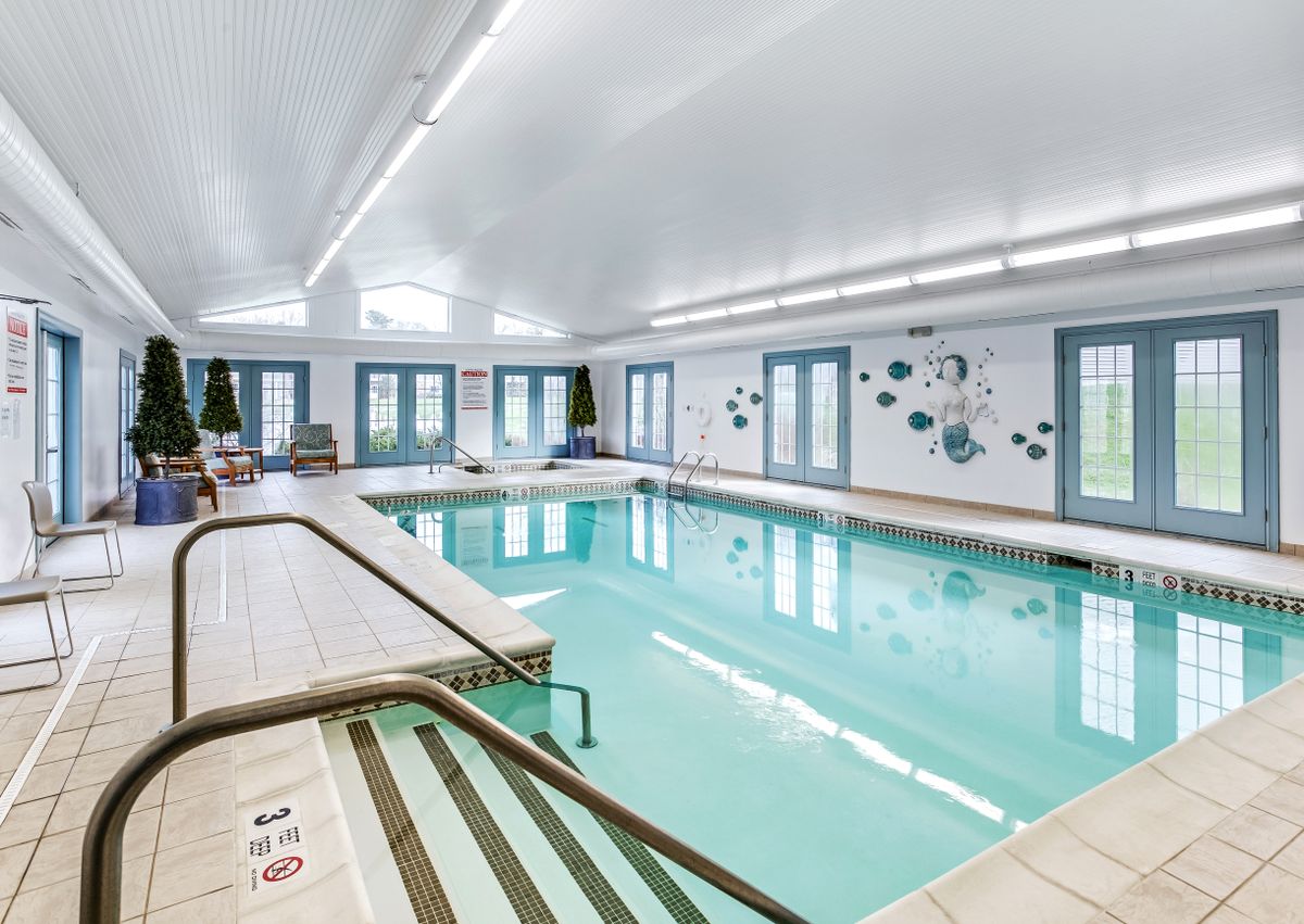 An indoor swimming pool area with bright lighting and seating.