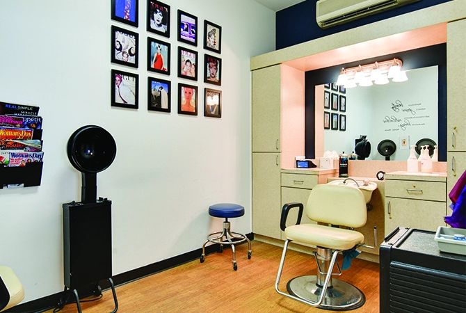 A cozy hair salon interior with styling chair, mirror, and wall decor.