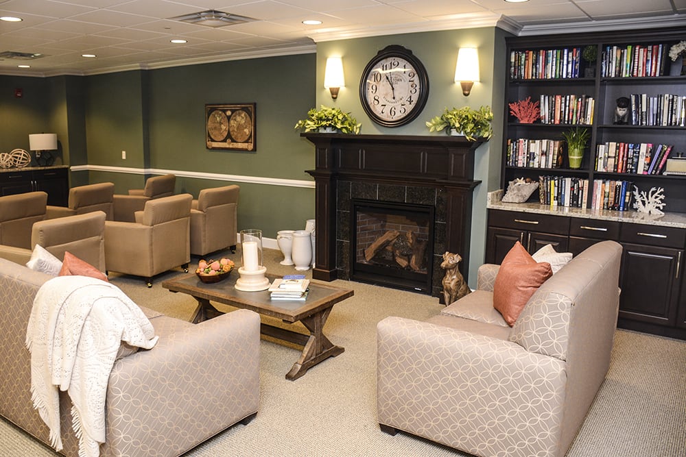 A cozy living room with comfortable seating, a fireplace, and a bookshelf.