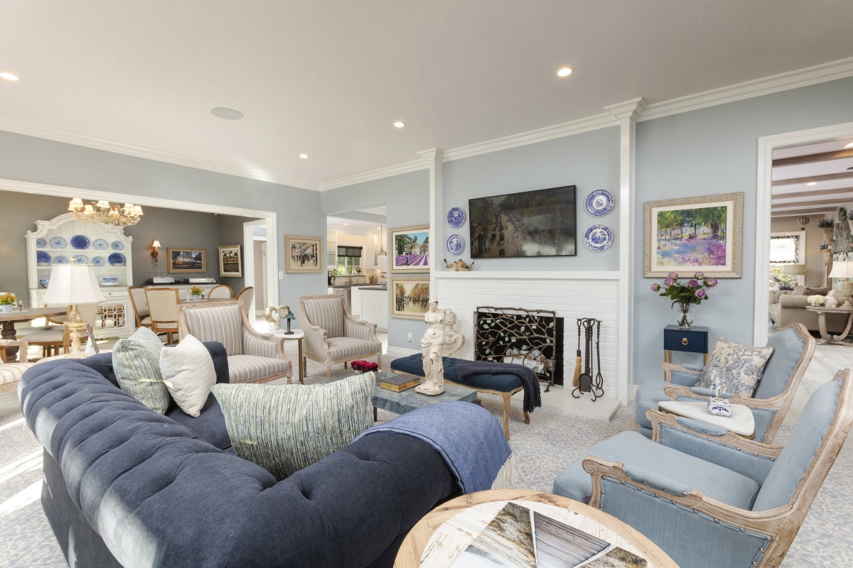 A modern and spacious living room with elegant furnishings, featuring a fireplace and a mounted television.