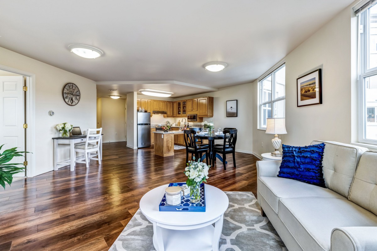 A spacious open floor plan featuring a modern living room and kitchen with stylish decor and wood flooring.