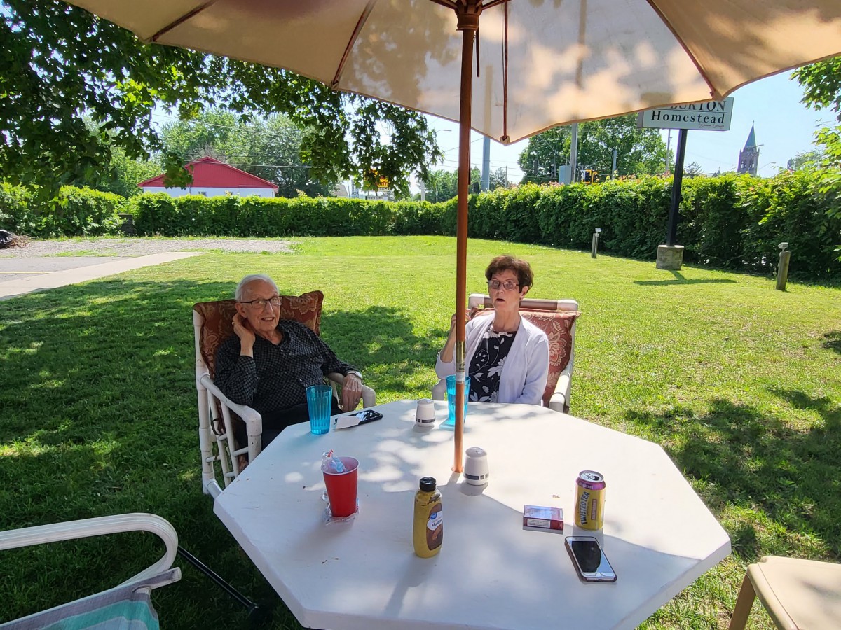 Two people sitting at a patio table under an umbrella on a sunny day.