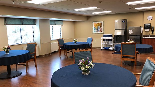 A well-lit dining area with tables and chairs, decorated with small flower arrangements.