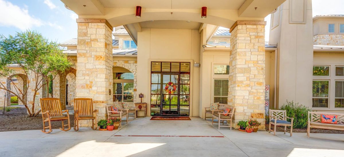 A welcoming entrance with large glass doors, flanked by chairs and decorative elements.