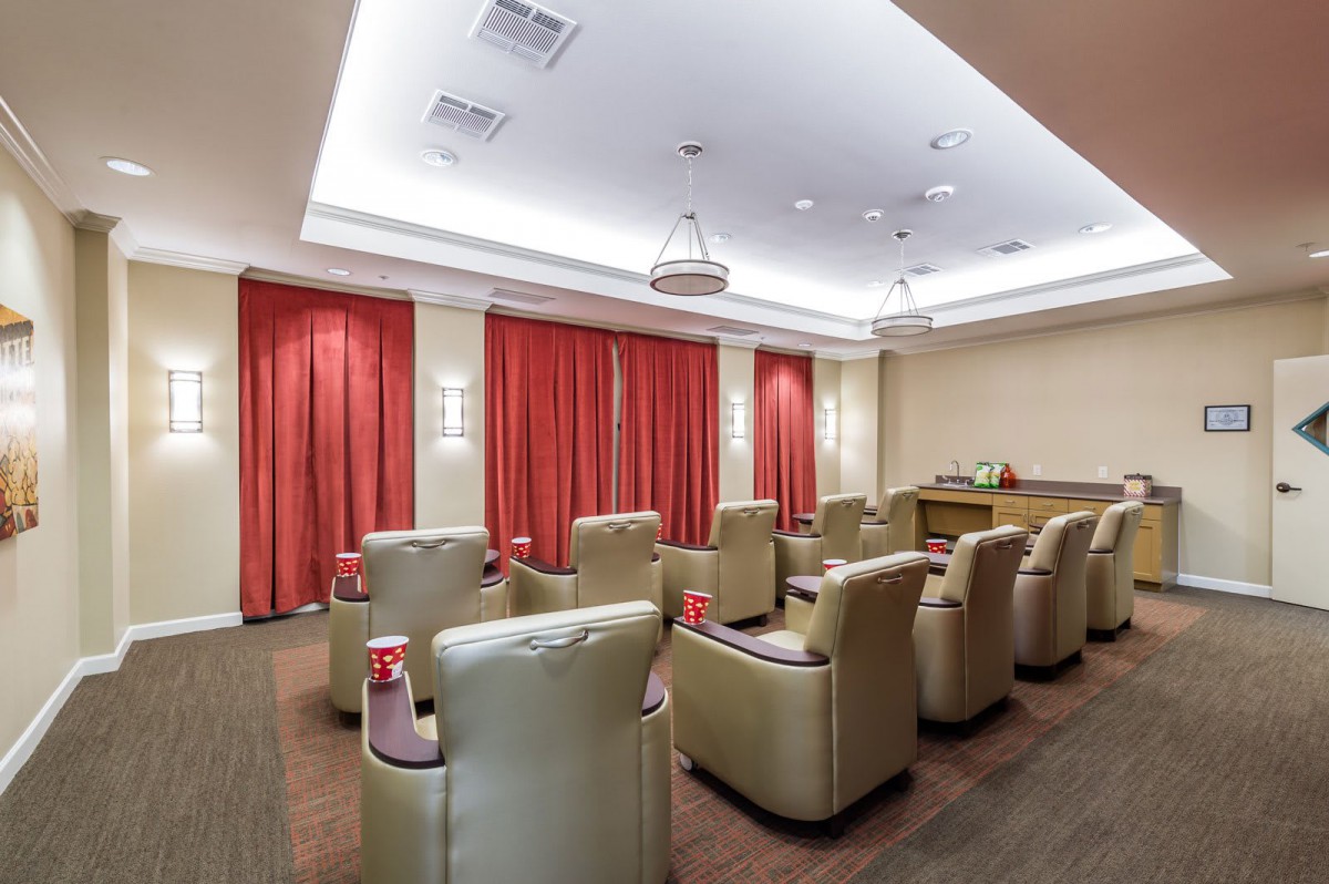 A cozy indoor theater room with comfortable recliner seating and red curtains.