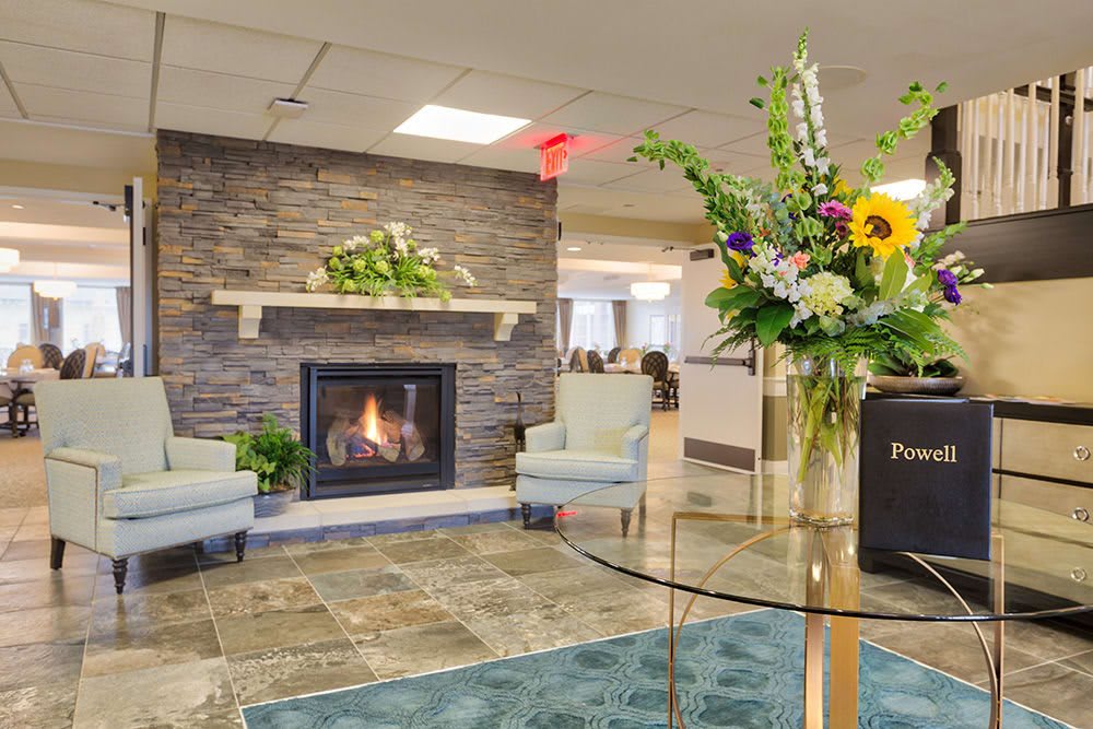 A modern lobby with a cozy fireplace, stylish chairs, and vibrant floral decor.