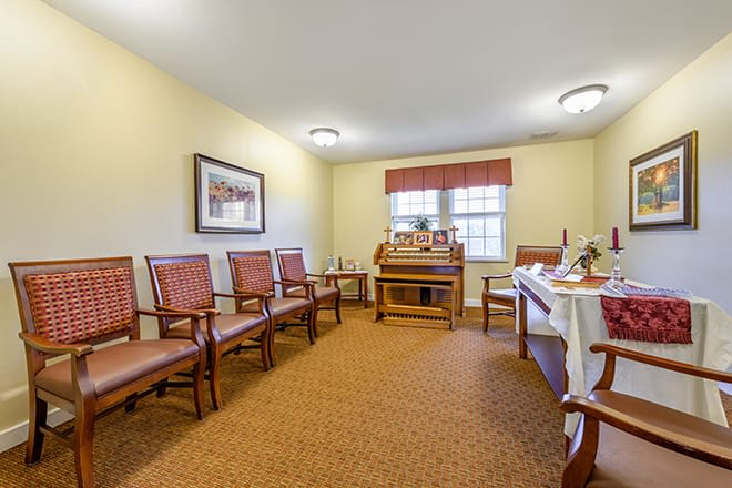 A cozy waiting room featuring multiple chairs, a wooden desk, and decorative artwork.
